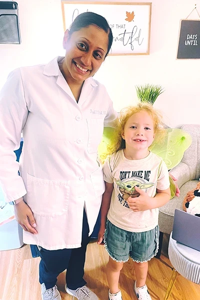 Dentist smiling with young patient in clinic