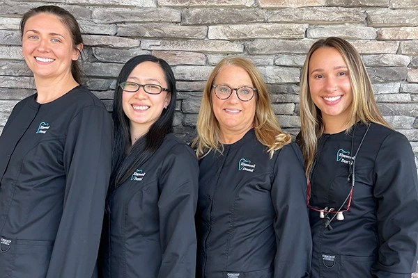 Staff in dark scrubs posing together against brick wall