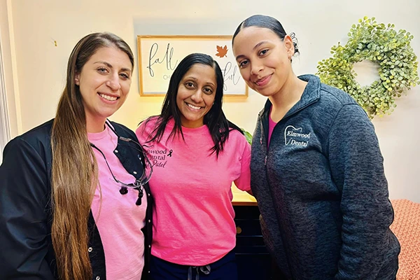Team members in pink and blue scrubs smiling for photo