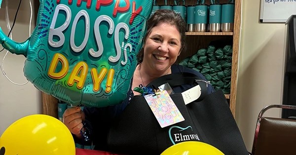 Staff holding &ldquo;Boss&rsquo;s Day&rdquo; balloon and yellow balloons