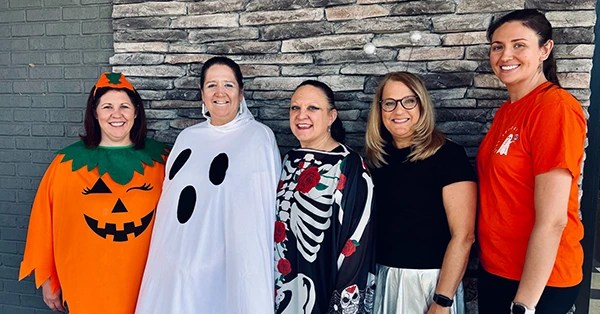 Team dressed in Halloween costumes &mdash; pumpkin, ghost, skeleton
