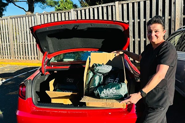 Team loading supplies into red car for community donation
